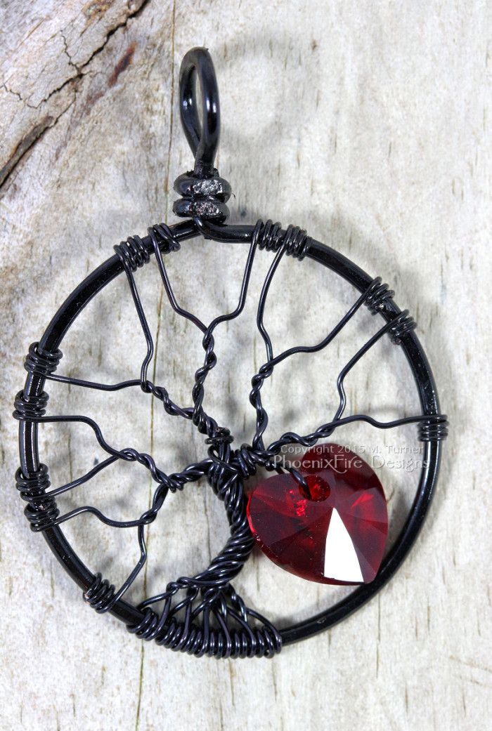 Handmade wire wrapped tree of life pendant black wire with siam red Swarovski crystal heart dangling from the silver wire branches by Phoenix Fire Designs on etsy.